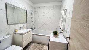 ein weißes Badezimmer mit Waschbecken und Badewanne in der Unterkunft Havana Studio-Alezzi Nord 10 (piscina&loc parcare) in Năvodari