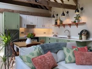 a living room with a couch and a kitchen at Pardlestone Farm Cottages in Kilve