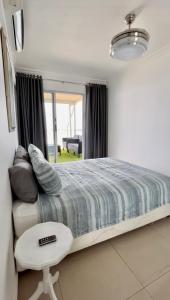 a bedroom with a large bed and a white table at 101 Camarque - Beachfront Apartment in Umdloti