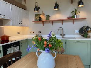 a kitchen with a vase with flowers on a table at Pardlestone Farm Cottages in Kilve