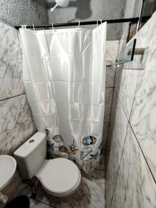 a bathroom with a toilet and a shower curtain at Apartamentos SOLAR PALMER in Cabo Frio