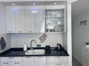 eine Küche mit weißen Schränken und einem Waschbecken in der Unterkunft Apartments 1126 Colony Beach with Pool Bat Yam Tel Aviv in Bat Yam