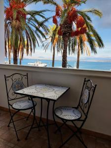 una mesa y 2 sillas en un balcón con palmeras en Casa Graziella, en SantʼAntìoco