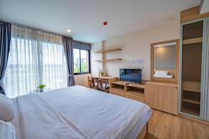 um quarto com uma grande cama branca e uma televisão em Rain Tree Condominium em Chiang Mai