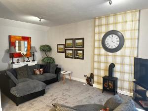 a living room with a couch and a clock on the wall at The Sandgate New Immaculate 1-Bed Apartment in Ayr in Ayr