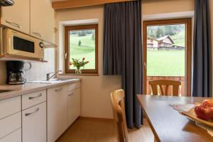 奧爾蒂塞伊的住宿－Garni Kostner，厨房以及带桌子和窗户的用餐室。
