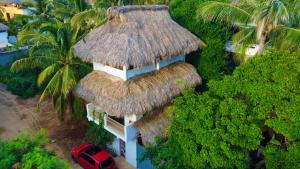 a small building with a straw roof and a red car at Casa shanti penthouse with AC in Puerto Escondido