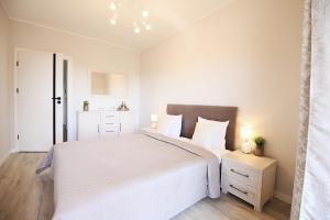 een witte slaapkamer met een groot bed en een nachtkastje bij Apartimento Angel River 9 in Wrocław