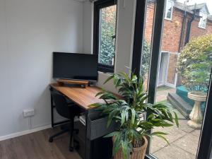 an office with a desk with a television and a plant at The Old Coach House in Stratford-upon-Avon