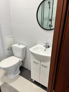 een badkamer met een toilet, een wastafel en een spiegel bij Apartament Podskarbińska in Warschau