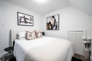 um quarto com uma cama branca e duas fotografias na parede em Luxury Stylish Home, Walk to Falls, Fire Pit&More em Cataratas do Niágara
