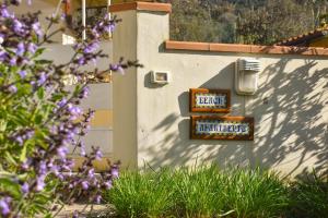 un panneau sur le côté d'un bâtiment avec des fleurs violettes dans l'établissement Beach apartments Isola d'Elba, à Portoferraio