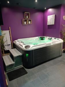 La salle de bains est pourvue d'une baignoire dans un mur violet. dans l'établissement Côté spa, 