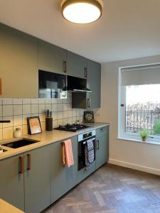 a kitchen with green cabinets and a sink and a window at Tanya's Place-Stylish flat in Marylebone in London