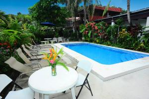 a table and chairs next to a swimming pool at Private Fully Furnished Home at Wide Mouth Frog Hostel Quepos in Quepos