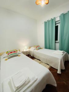 2 łóżka w pokoju z niebieskimi zasłonami w obiekcie À do Matias w mieście Mourão