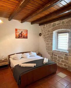 a bedroom with a bed and a stone wall at Holiday Houses Luan in Poreč