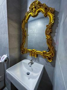 ein Badezimmer mit einem Waschbecken und einem mit Gold gerahmten Spiegel in der Unterkunft Disneyland Theme DFB homestay 03 Gala City Armadale Residence in Kuching