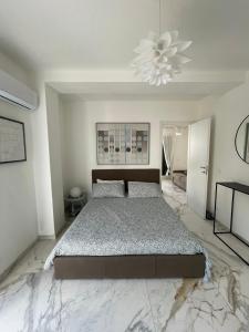a white bedroom with a large bed and a chandelier at Beach apartments Isola d'Elba in Portoferraio