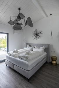 ein weißes Schlafzimmer mit einem Bett und einer Decke in der Unterkunft KANANI am Hainer See in Neukieritzsch