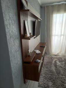 a bedroom with a desk and a bed with a window at Apto da Andreia in Praia Grande