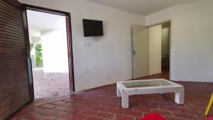 a room with a table and a tv and a door at Casa inteira, com sauna, piscina ozonizada, praia Enseada dos Corais, Cabo de Santo Agostinho, Pernambuco, Brasil in Cabo de Santo Agostinho