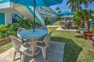 eine Terrasse mit einem Tisch, Stühlen und einem Sonnenschirm in der Unterkunft Horizon by the Sea Inn in Fort Lauderdale