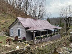 a small house with a red roof on a hill at Plum Crooked Poets Cottage - Walk to Town - Luxury King Bed - Near Asheville - Excellent Wi-Fi in Marshall