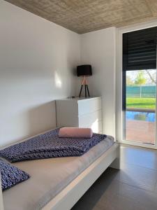 a white bedroom with a bed and a window at VOO residence in Malečnik