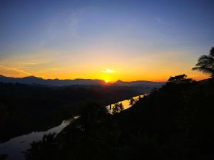 einen Sonnenuntergang über einem Fluss mit Sonnenuntergang in der Unterkunft Mahaweli View Inn in Kandy