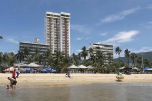um grupo de pessoas numa praia com edifícios em Luxurious Apartment, Oceanfront, spectacular view em Acapulco