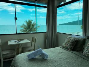 um quarto com uma cama e vista para o oceano em Parada Beach Beira-Mar e Aptos 70m do Mar em Florianópolis