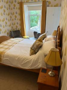 a bedroom with a bed with a lamp and a window at Conval House Bed And Breakfast in Dufftown
