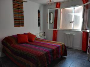 um quarto com uma cama com um cobertor colorido e uma janela em Chambre(s) d'hôte chez Mam's em Beaucaire