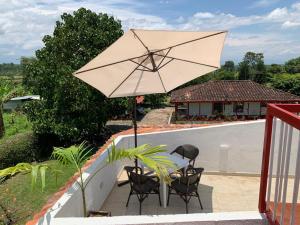 a patio with a table and chairs and an umbrella at Finca Monte del Sol in Quimbaya