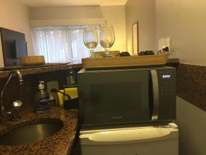 a kitchen with a microwave and two glasses of wine at Flat incrível e acessível ao lado da Paulista in São Paulo