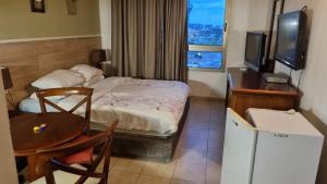 Habitación pequeña con cama, mesa y TV. en beach Apartments, en Haifa