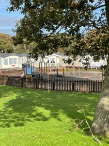 a playground in a park with a fence and a tree at Nodes Point Sandy Bay AP27 affordable ferry prices available in Saint Helens