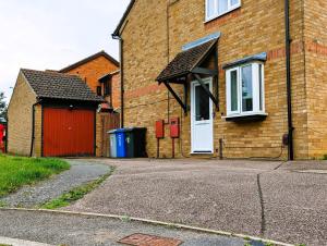 una casa de ladrillo con garaje rojo y puerta blanca en 6 Guests * 4 Bedroom * Free Wi-Fi en Burton Latimer