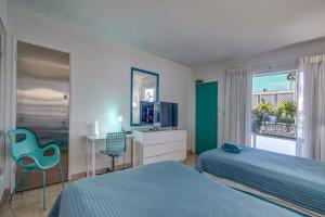 1 dormitorio con 2 camas, escritorio y TV en Horizon by the Sea Inn en Fort Lauderdale