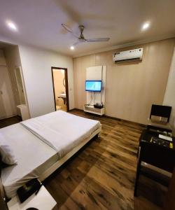 a bedroom with a bed and a desk and a television at Hotel Royal Brooks in Chandīgarh