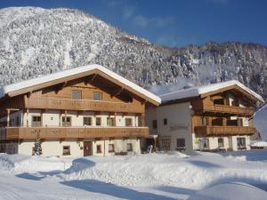 a ski lodge in the snow in front of a mountain at Pension&Appartements Marxenhof in Pertisau