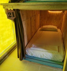 a small bed in a room next to a window at Hostel Tropico 20 PDC in Playa del Carmen