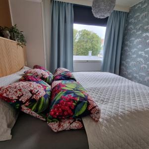 ein Schlafzimmer mit einem Bett mit Kissen und einem Fenster in der Unterkunft Kodikas ja viihtyisä kaksio keskustassa in Uusikaupunki