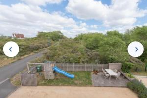 un patio trasero con un tobogán y un parque infantil en Cosy 6P family home 'Notre Nid' close to the beach 300m Oostduinkerke - Belgian seaside, en Oostduinkerke-Bad