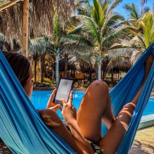 una mujer tendida en una hamaca con una tablet en La Casa de Sebas - Pool Beach Hotel Mancora, en Máncora