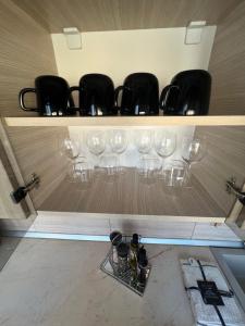 a shelf with wine glasses and bottles on it at Apartament Wide View in Buzău