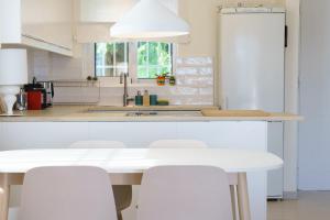 a white kitchen with a white table and chairs at Maia beach house in Rafina