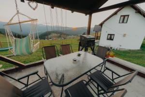 eine Terrasse mit einem Tisch, Stühlen und einem Grill in der Unterkunft Pleta View in Vatra Dornei