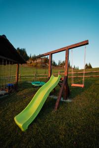 a playground with a slide and swings in a field at Pleta View in Vatra Dornei